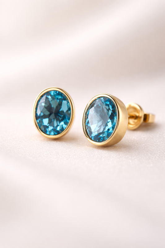 Aretes de topacio azul de corte oval en oro