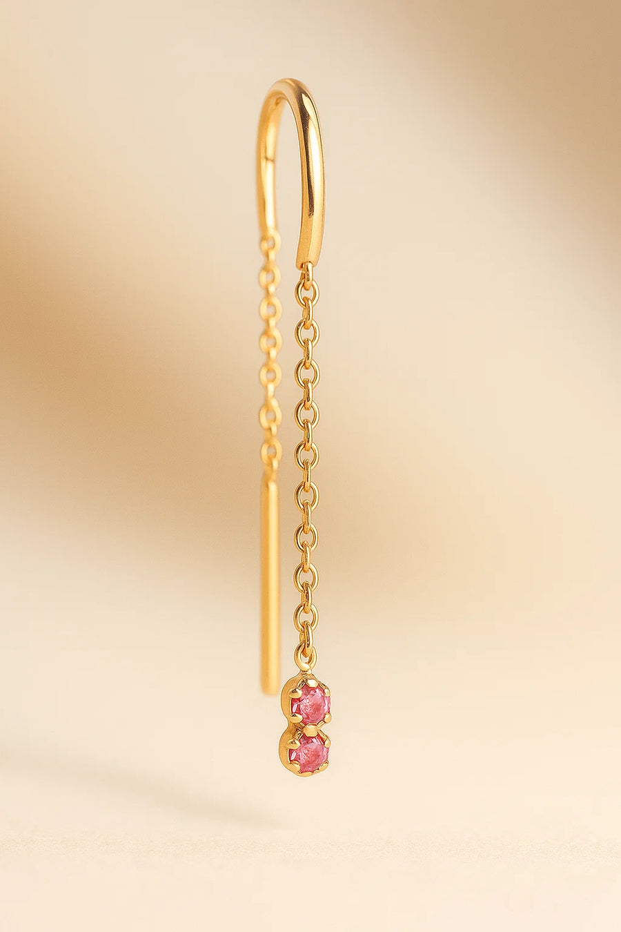 Arete individual con zafiro rosa colgando de una cadena fina de oro 18k